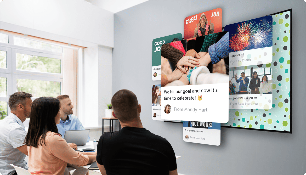 A group inside an office looking at a big screen displaying a kudoboard filled with appreciation for employees