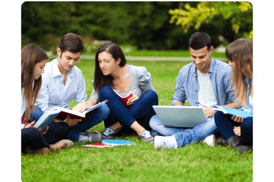 Group of university students looking at books and laptops on lawn