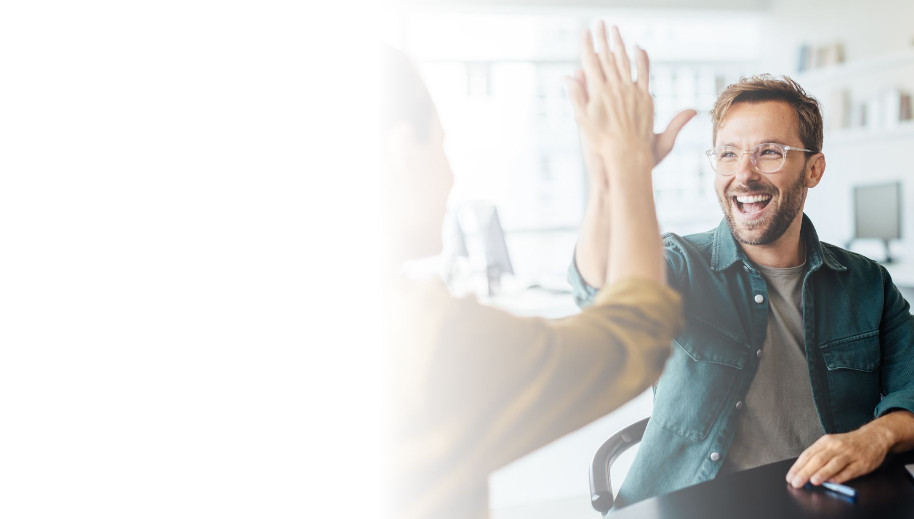 Two people in office giving high five and offering congratulations