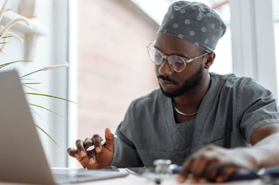 Doctor looking at phone on desk with laptop