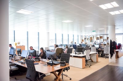 Crowded office with monitors and people