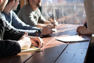 Group of people talking and writing on notepad