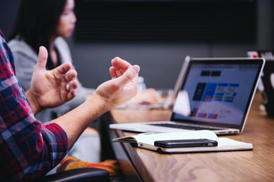 Man explaining with hands in front of laptop