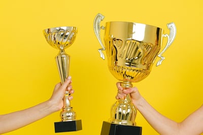 Two hands holding trophies