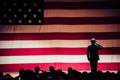 Full American flag banner with service member saluting