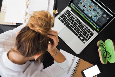 Person putting head in hands while looking at laptop