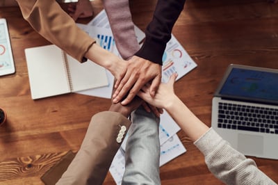 People placing hands together over meeting table