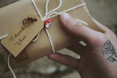 Hand holding an envelope with a thank you tag attached