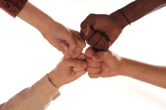 Four hands fist bumping together