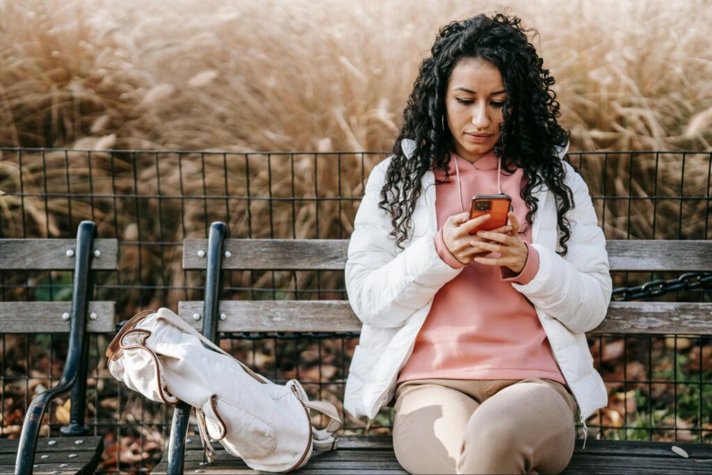 Person on park bench texting eCard on phone