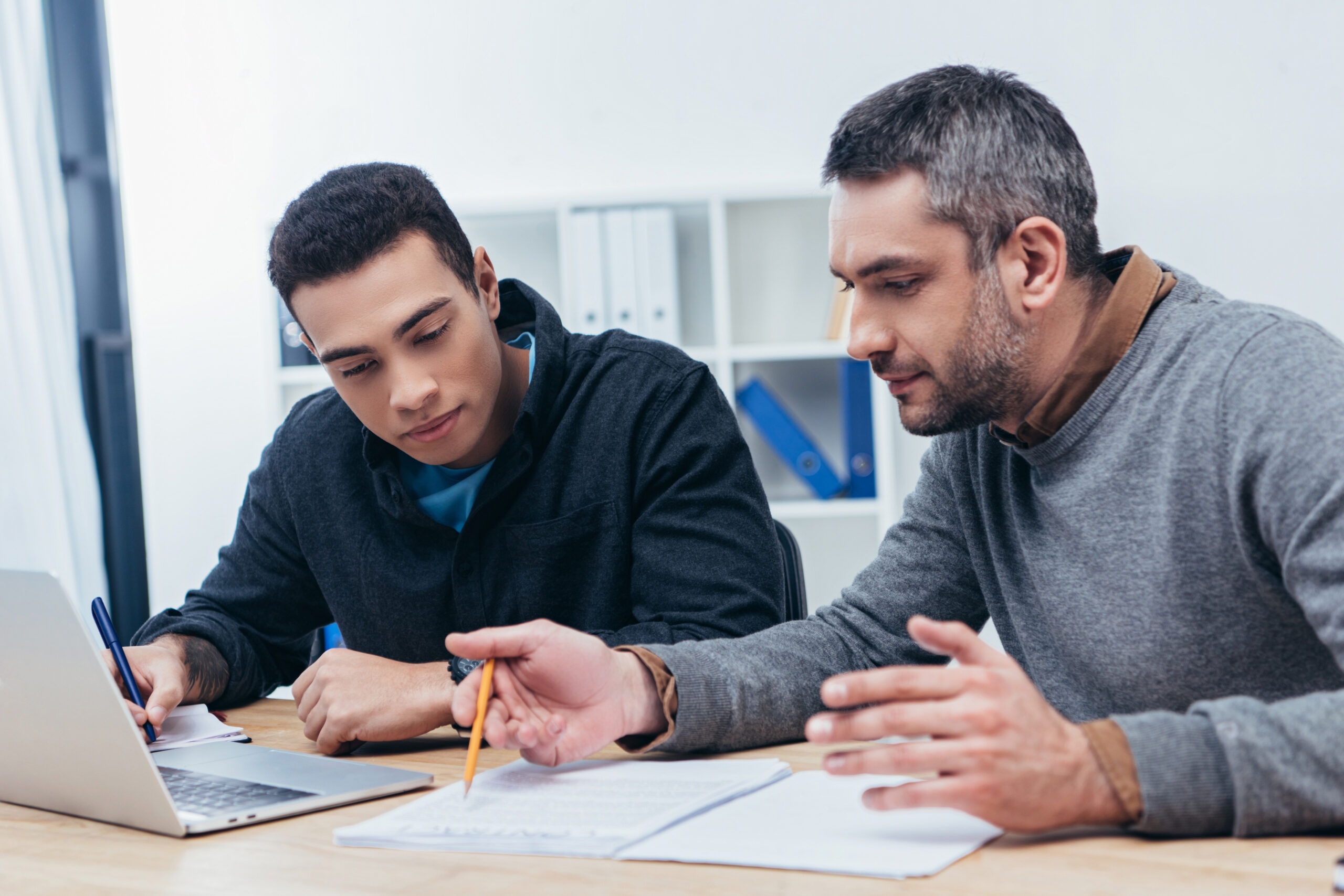 Mentor working with younger person on documents