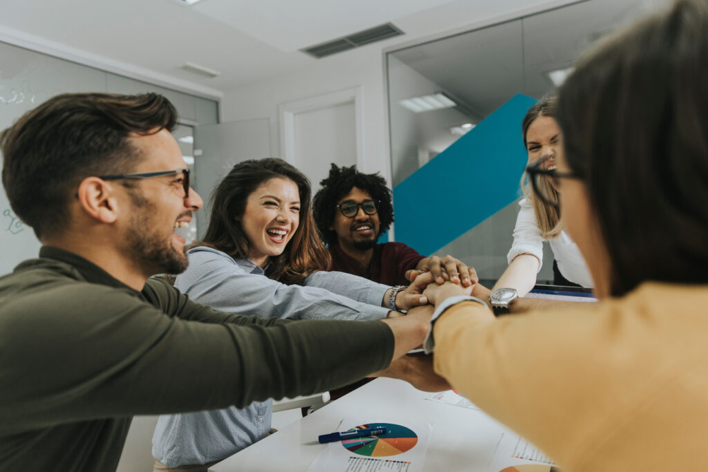 Team of young employees placing hands together in a circle