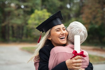 Older person hugging female graduate with diploma
