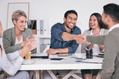Coworkers getting congratulations on the new job message and handshake from friend