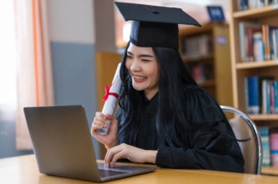 Smiling graduate looking at graduation eCard on laptop