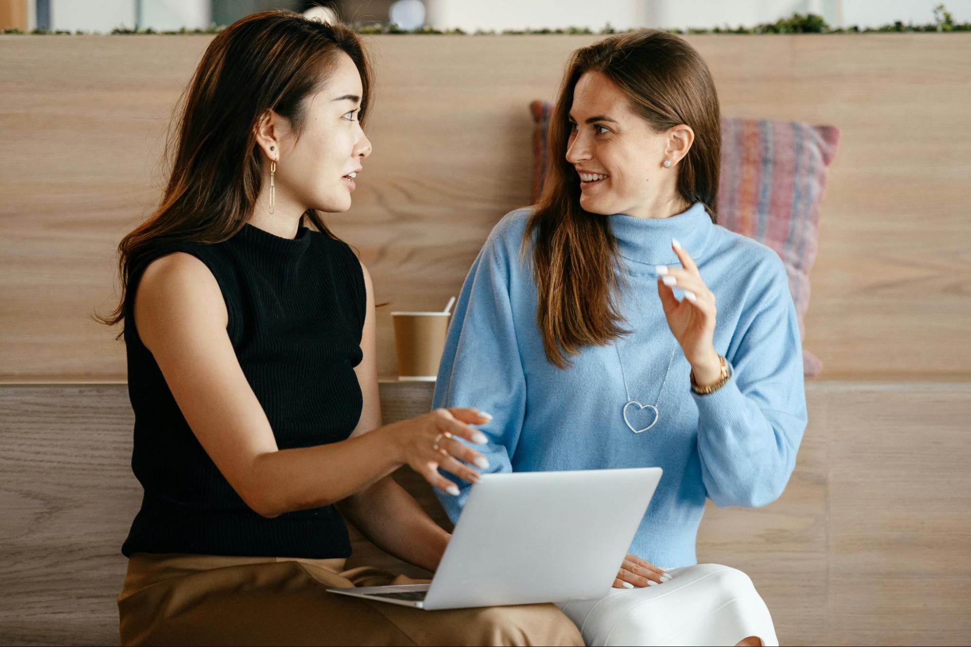 Two employees working together on laptop and celebrating success