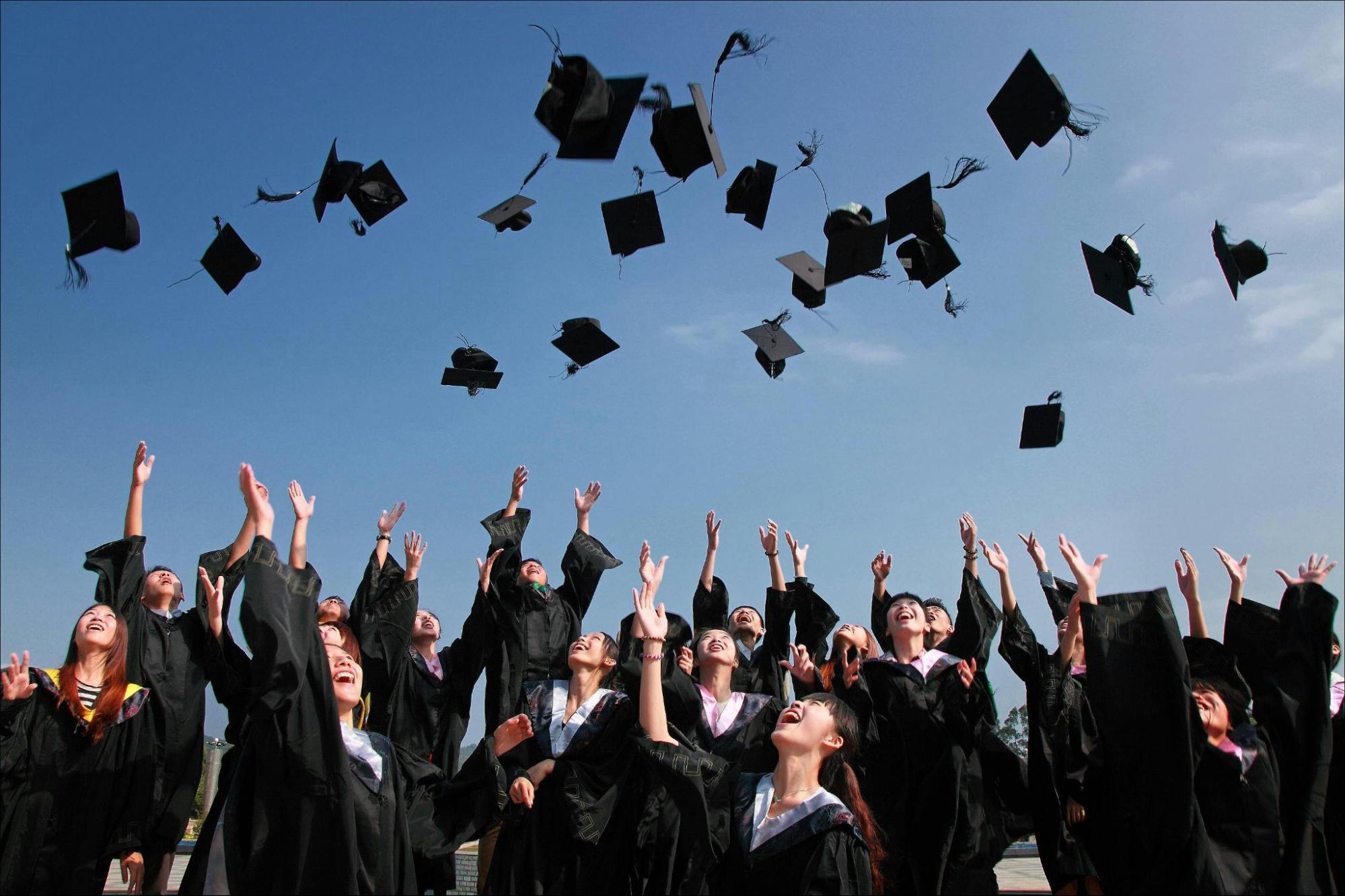 Graduates throwing caps up into the air