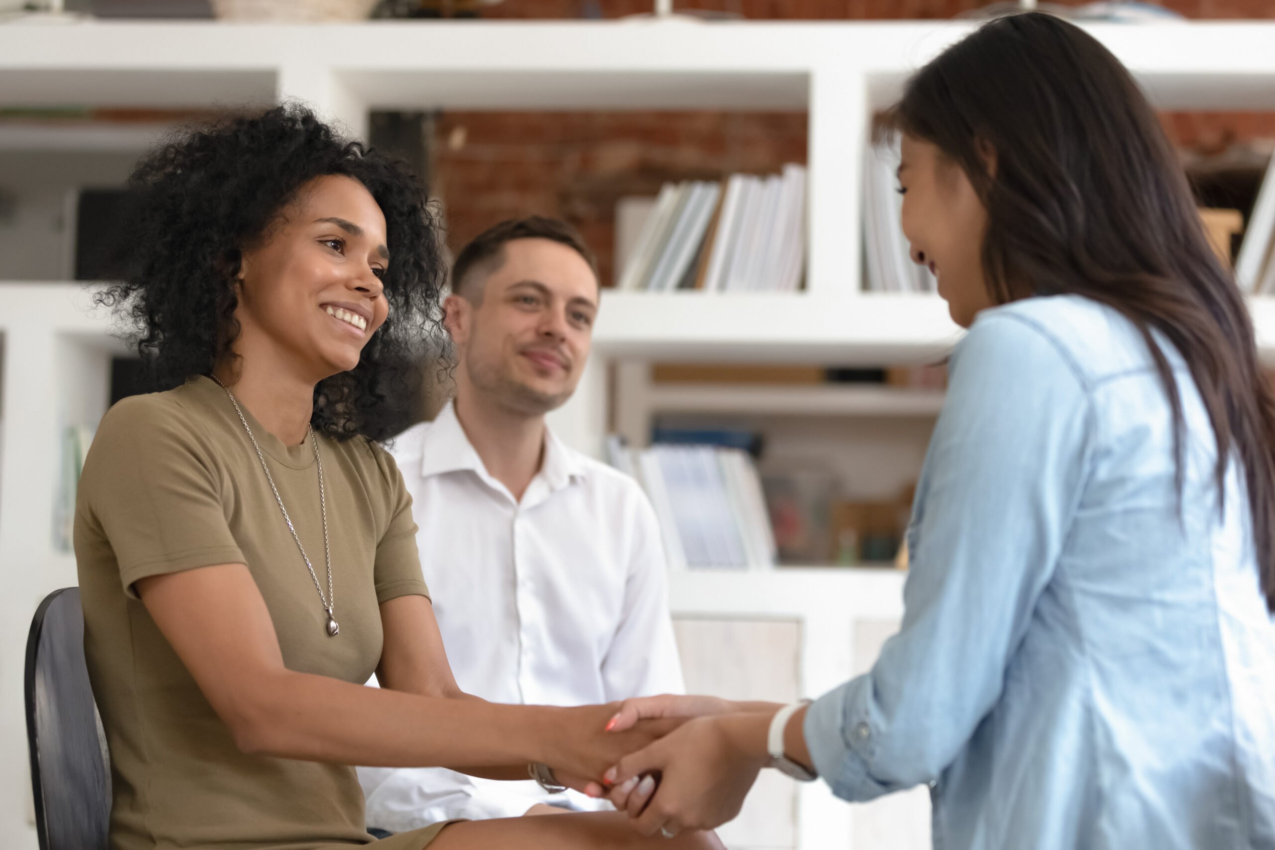 Two smiling employees holding hands in support