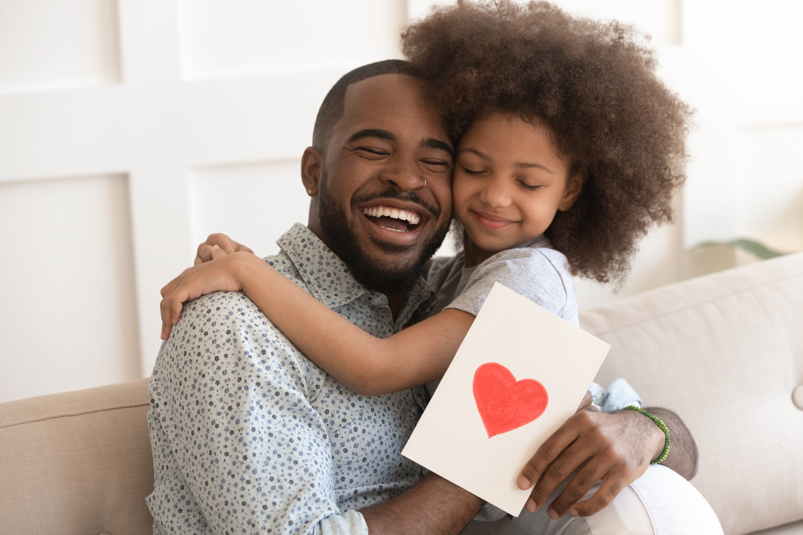 Man hugging daughter after receiving. card with Father's Day messages