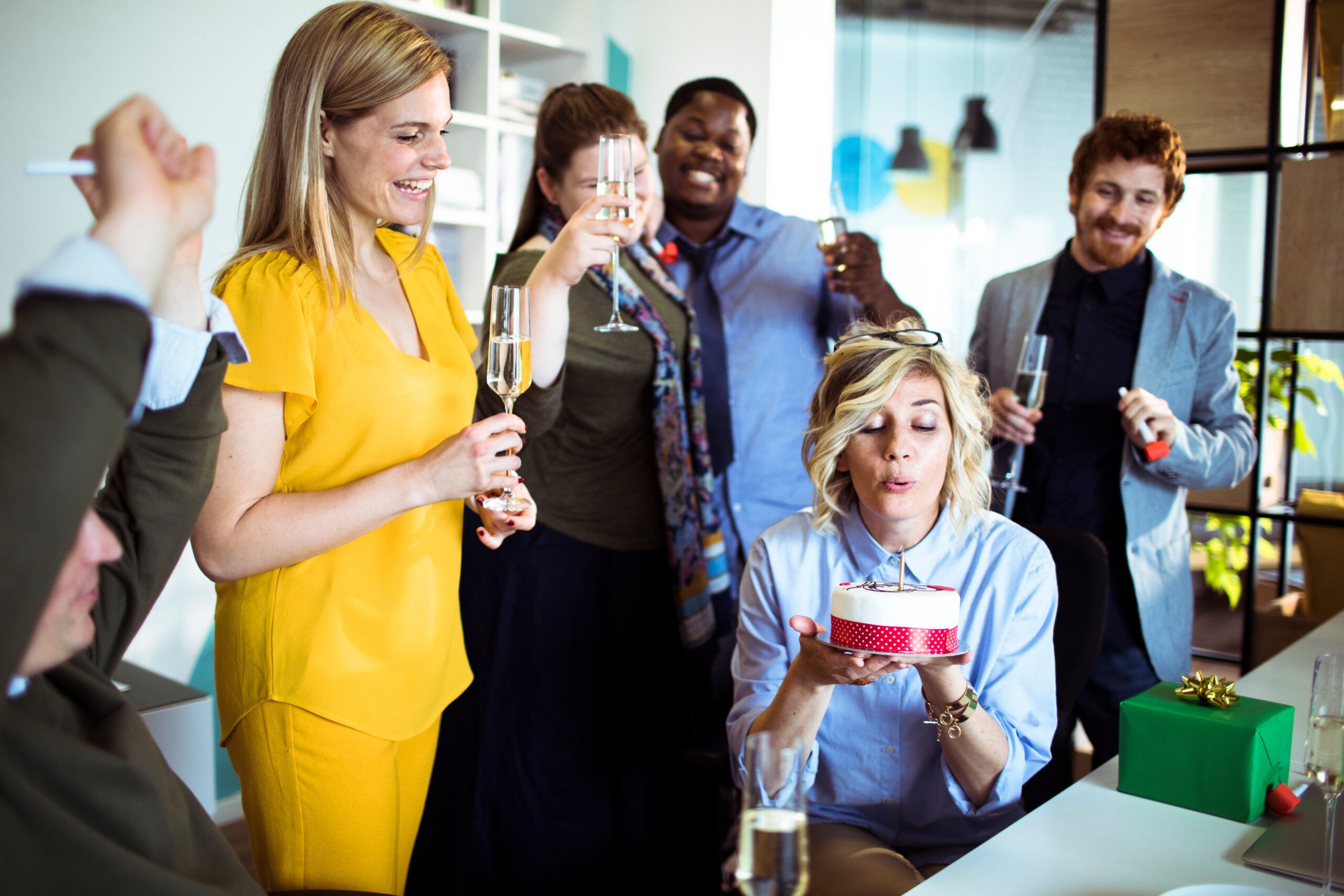 coworkers gathering around an employee blowing out a birthday cake