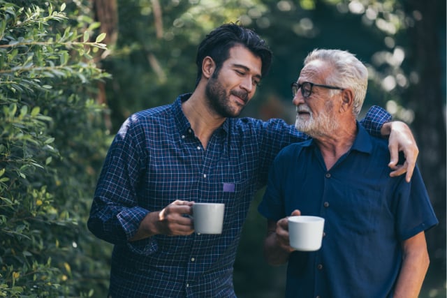 Son giving dad happy father's day messages in garden with coffee