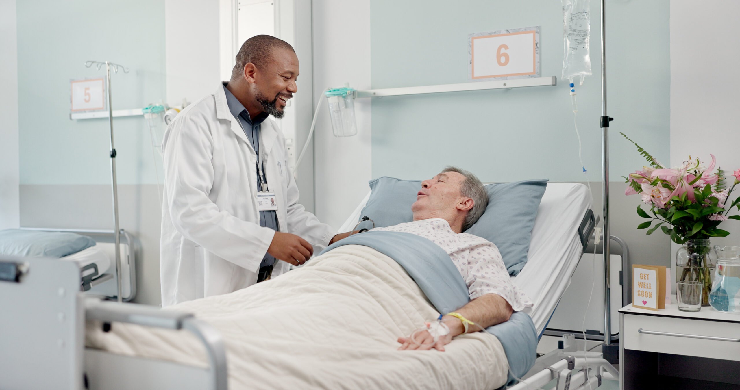 A doctor holds the hand of a patient in bed